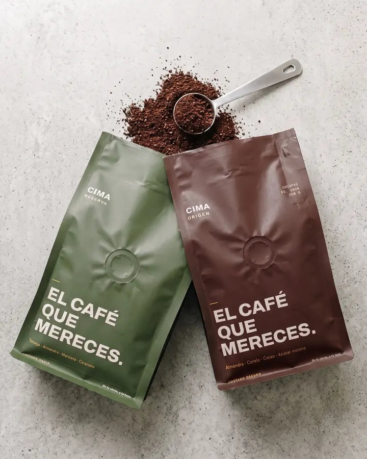 Bolsas de CIMA Reserva y CIMA Origen con café molido y una cuchara