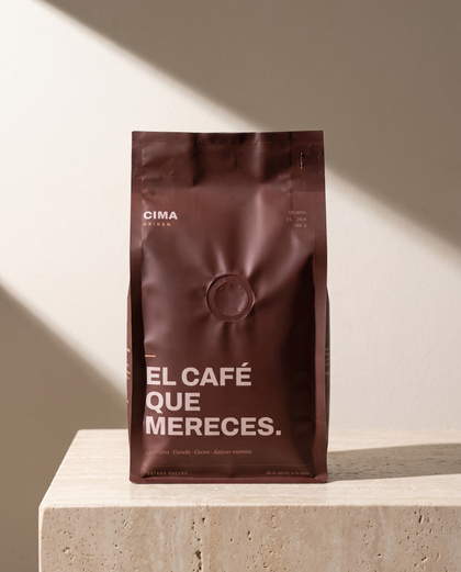 Bolsa vino de CIMA Origen de 500 g sobre un bloque de travertino, con luz lateral y sombra suave al fondo