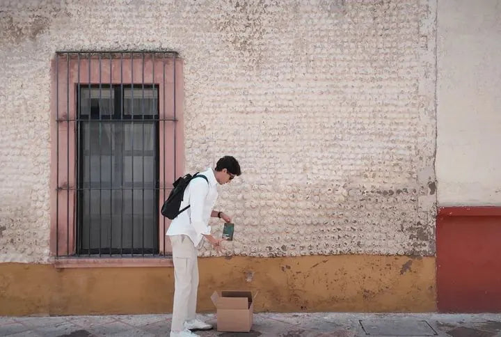 Horacio en la calle, junto a una caja de envío, con una bolsa de CIMA en la mano